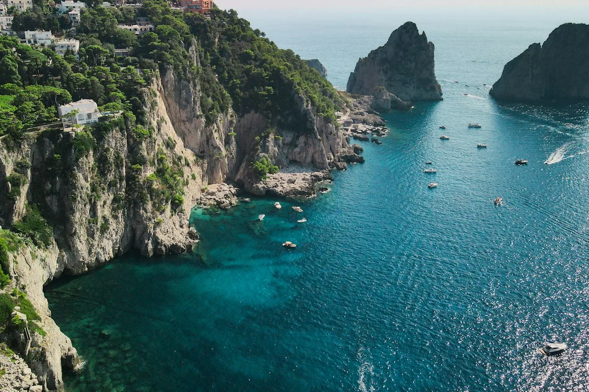 Barche in gita davanti a una costa rocciosa, viste dall'alto