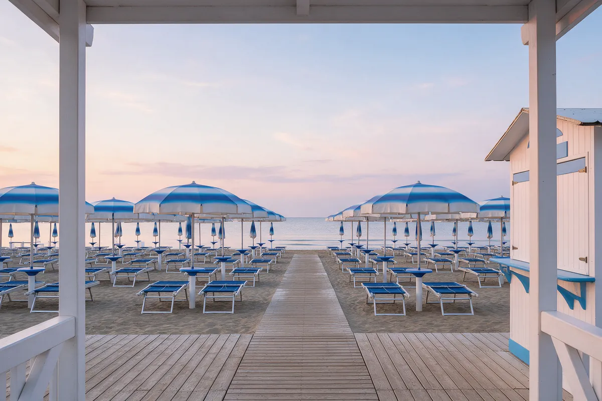Ingresso di un lido all'alba, con la passerella tra le file di ombrelloni